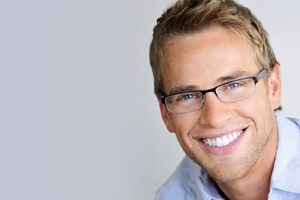 A young man wearing glasses and smiling