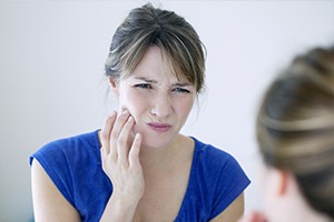 Woman grimacing and holding cheek