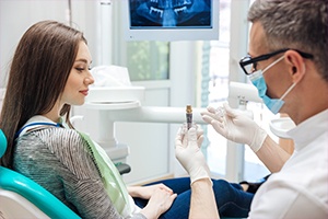 Dentist showing female patient dental implant model